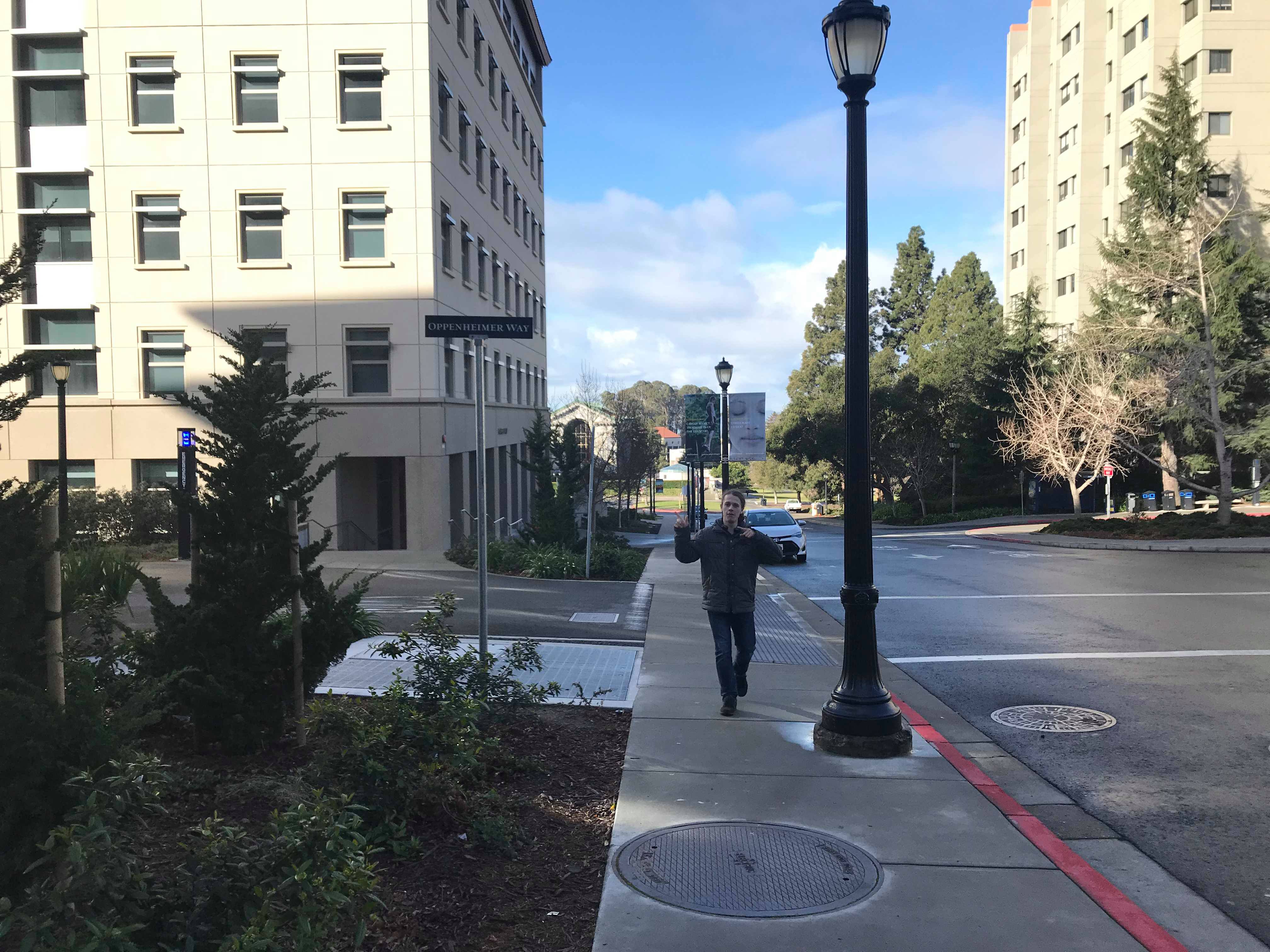 Roman walking towards the camera pointing at the street names Oppenheimer way