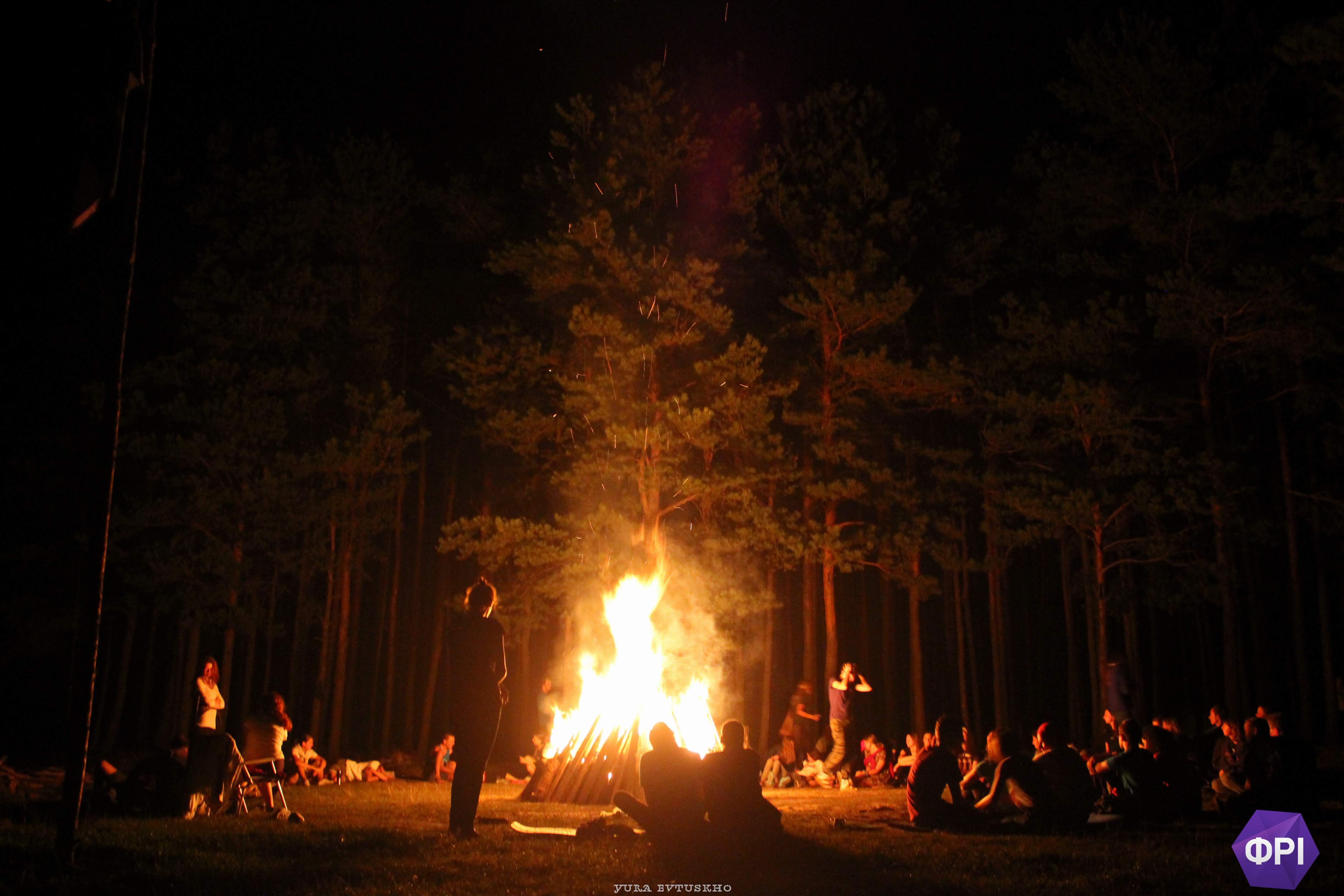 A giant fire, surrounded by a semicircle of people a safe distance away.