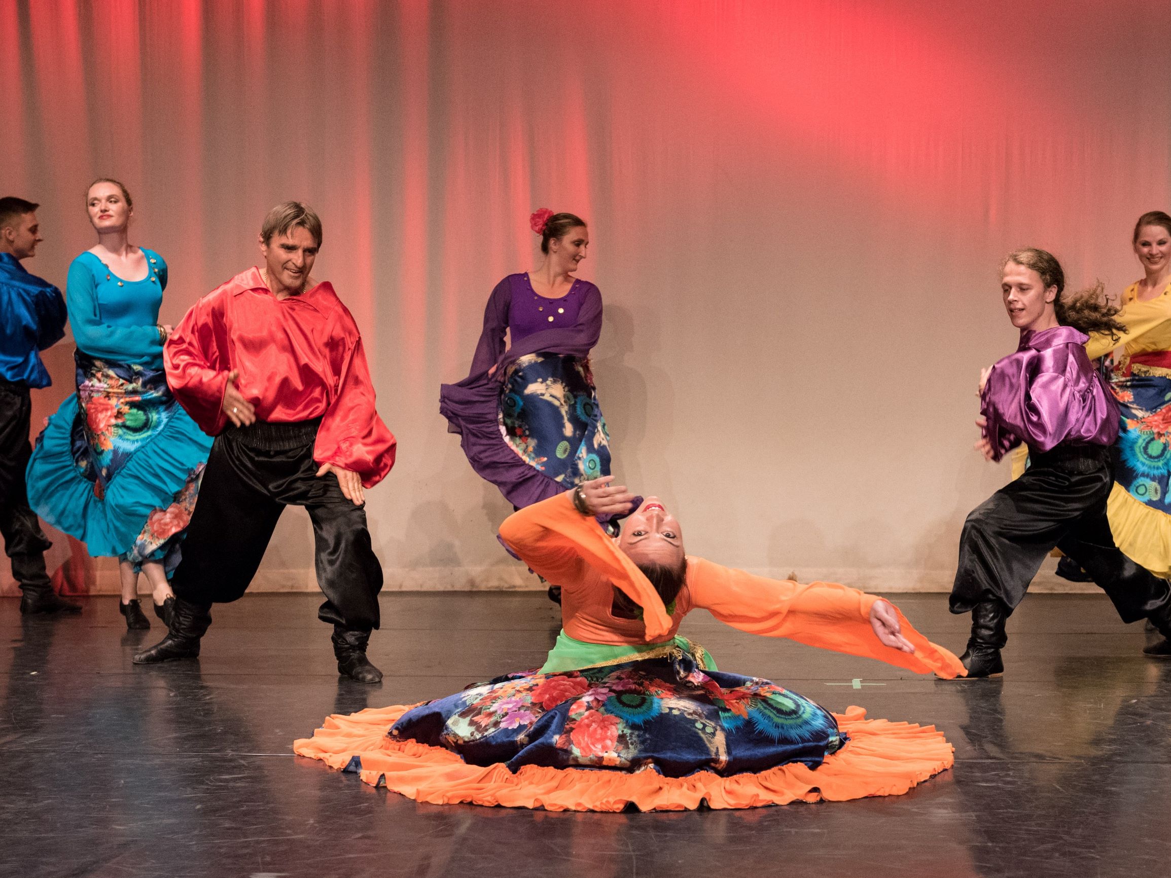 A girl is dancing on the floor in the middle, two guys are applauding her. Other people are dancing in the background.